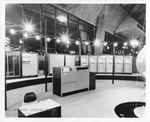 Photograph of the UNIVAC system, with the UNIVAC printer in the center front and other computing machines in a semicircle behind.