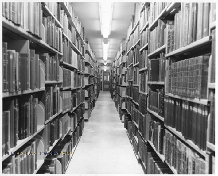 Photograph from the University of Illinois Archives of one aisle in the bookstacks of the Main Library with several shelves full of books