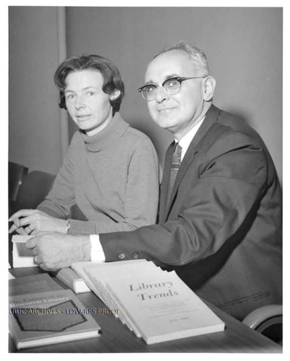 Photo from the University of Illinois Archives of Herbert Goldhor and Barbara Donagan seated at a table with various publications, including "Library Trends"