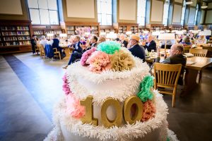 Anniversary cake in foreground and event participants in background